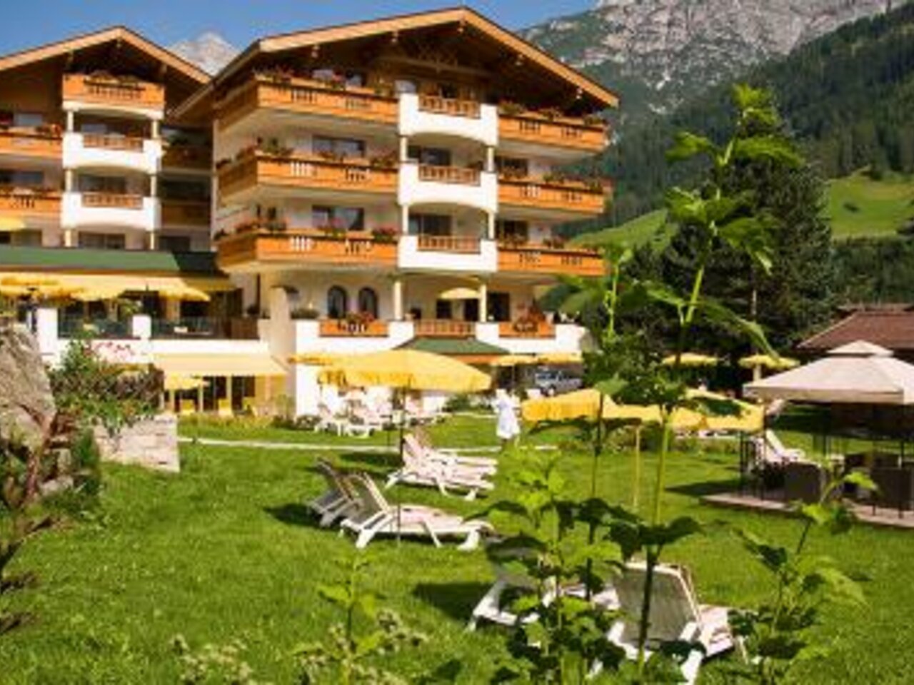 Hotel with balconies and yellow parasols against a mountain backdrop