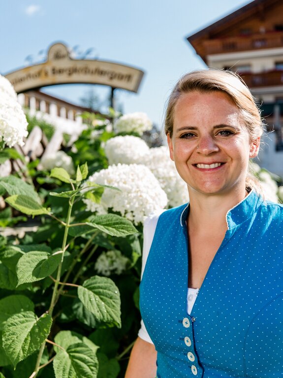 Gastgeberin Martina im Dirndl vor Hortensien und dem Stubaierhof