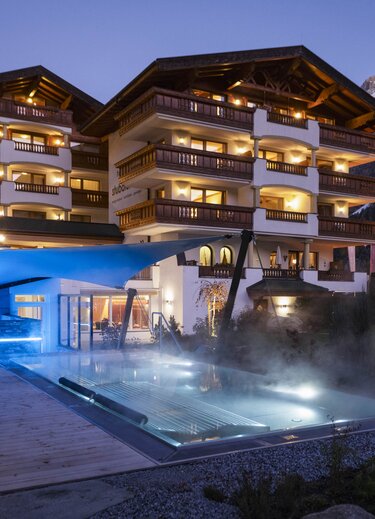 Stubaierhof mit Pool und Bergen im Hintergrund bei Dämmerung