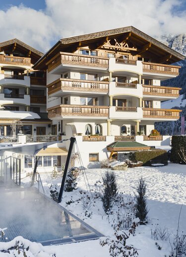 Hotel building in winter with snow and steam against a mountain backdrop