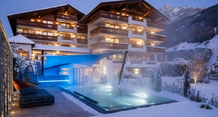 Abendliche Außenansicht des Hotels Stubaierhof mit beheiztem Pool im Schnee