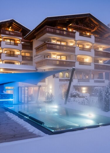 Abendliche Außenansicht des Hotels Stubaierhof mit beheiztem Pool im Schnee