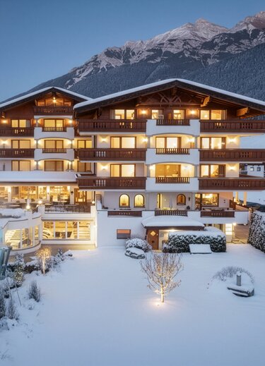 Beleuchtetes Hotel Stubaierhof mit Außenpool in verschneiter Winterlandschaft