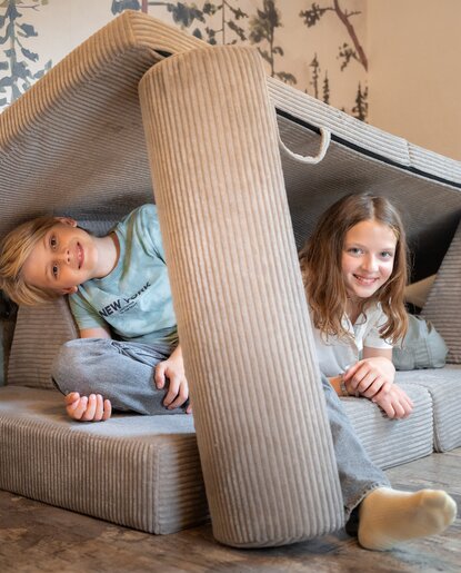 Lächelnde Kinder in gemütlicher Kissenhöhle