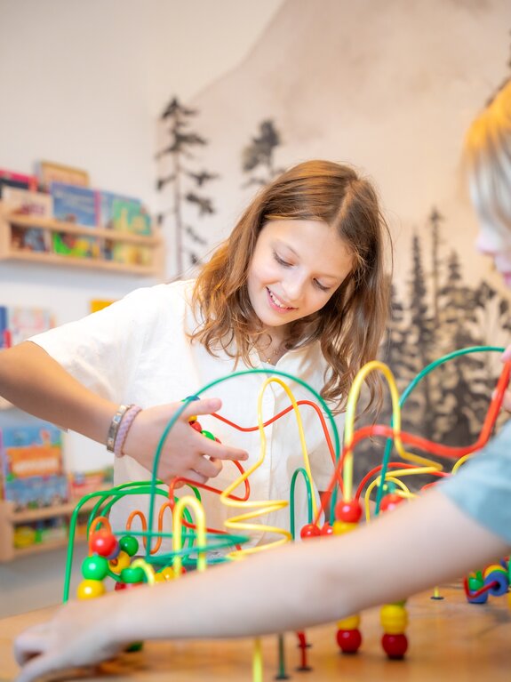 Lächelndes Mädchen spielt mit bunter Motorikschleife