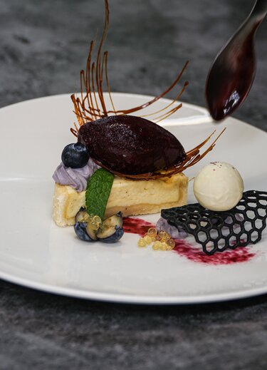 Dessertteller mit Käsekuchen, Blaubeeren, Schokoladensauce und essbarer Dekoration
