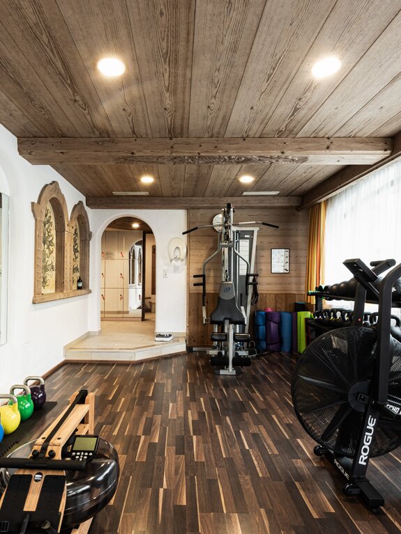 Fitness room with wooden ceiling, exercise equipment and a view into a hallway