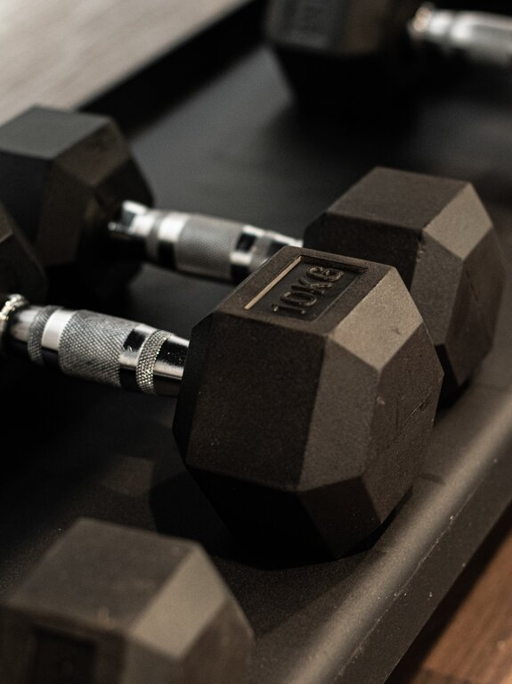 Black dumbbells with silver handles lie on a shelf