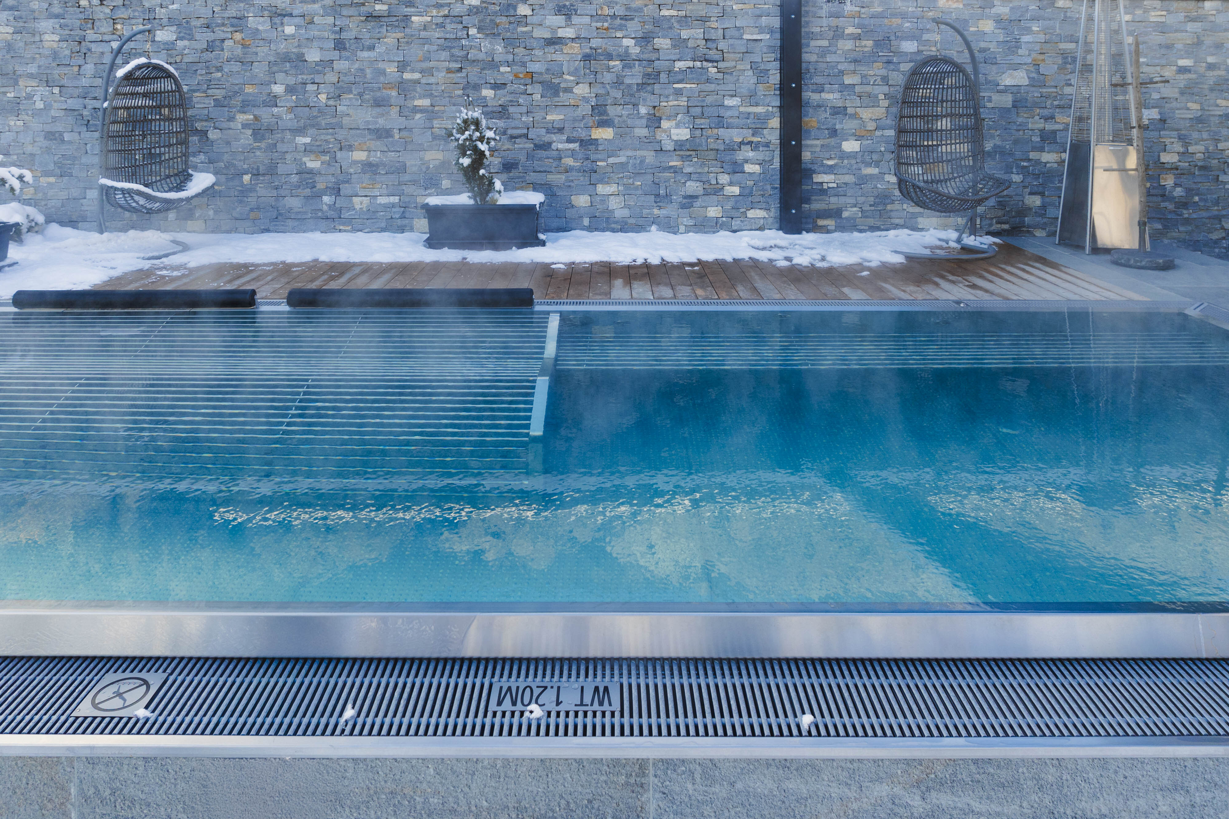 Winterlicher Außenpool mit Steinmauer und Schnee