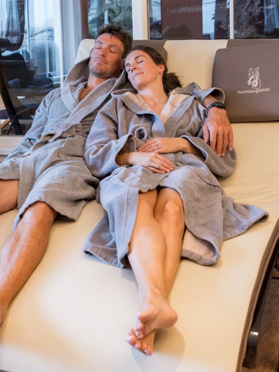 Entspanntes Paar in Bademänteln auf Liegen