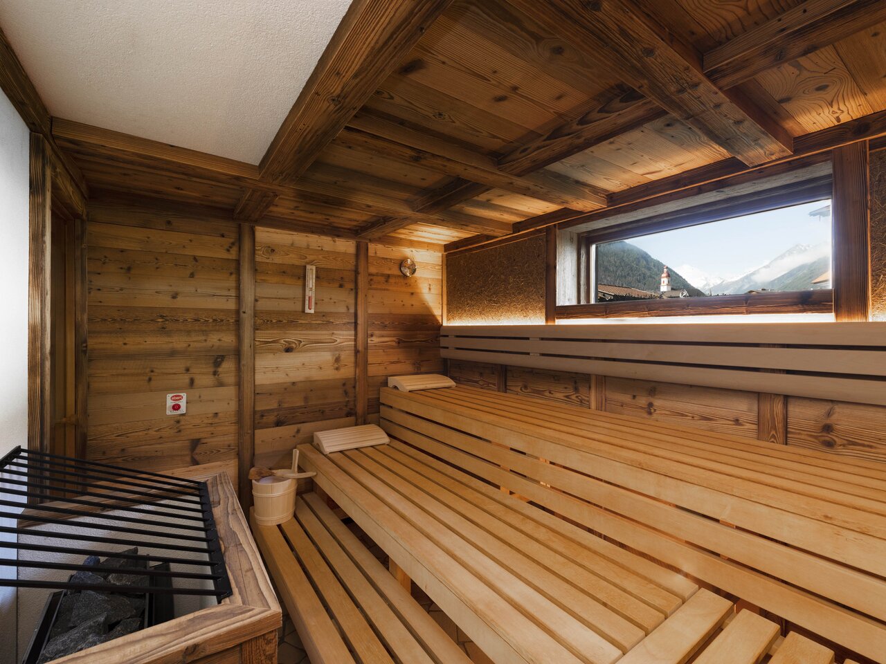Holzsauna mit Liegeflächen, kleinem Fenster und Ofen