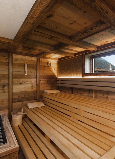 Holzsauna mit Liegeflächen, kleinem Fenster und Ofen