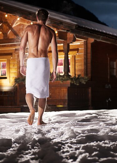 Mann mit Handtuch geht nach Sauna in Schnee