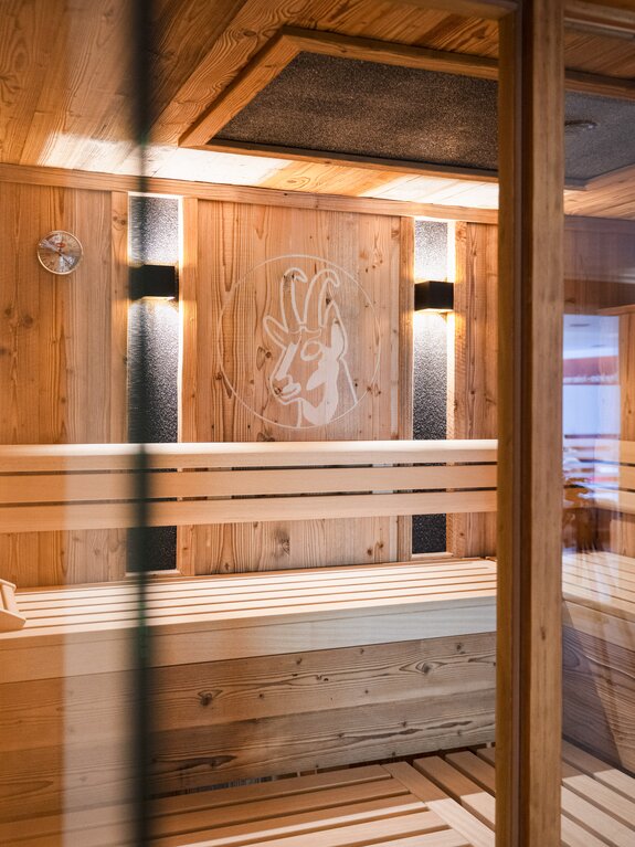 Holzsauna mit Bänken, Glaswand und Ziegenmotiv an der Wand