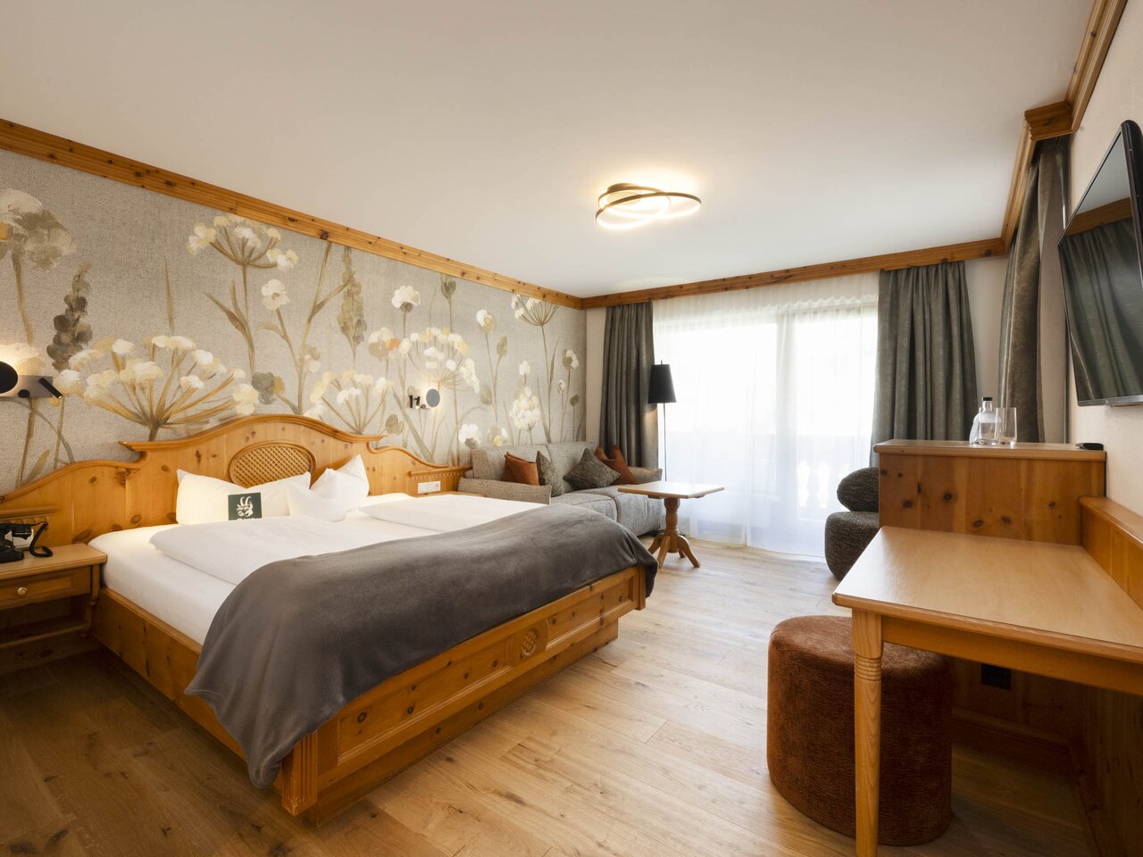 Alpines Hotelzimmer "Stubaier Zirbe" mit floraler Wandtapete und Holzboden