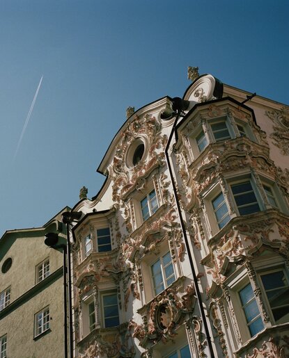 Verziertes Gebäude in Innsbrucks Altstadt vor blauem Himmel