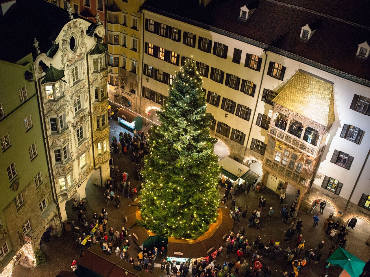 Christmas market in Innsbruck with a large Christmas tree and crowd at night