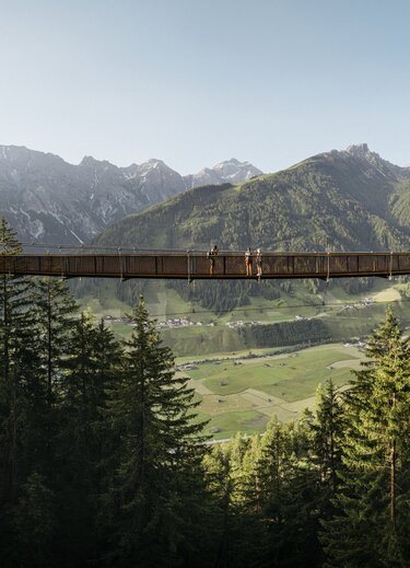 Hängebrücke im Stubai vor Bergpanorama und grünen Tälern
