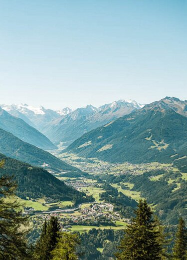 Blick ins Stubaital mit grünen Hängen und schneebedeckten Bergen im Hintergrund