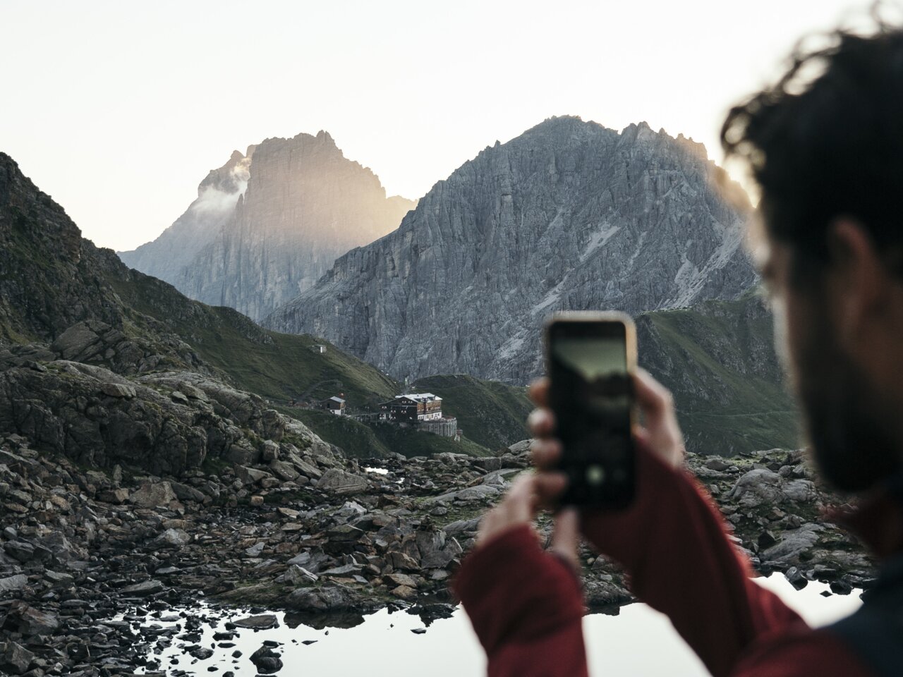 Mann fotografiert Berglandschaft mit Smartphone