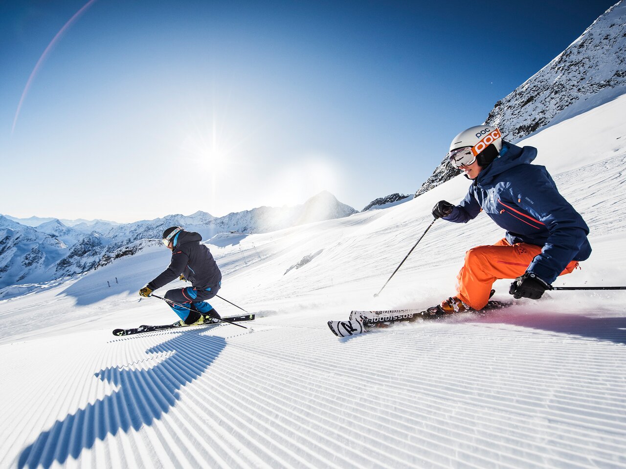 Zwei Skifahrer auf präparierter Piste am Stubaier Gletscher bei strahlendem Sonnenschein
